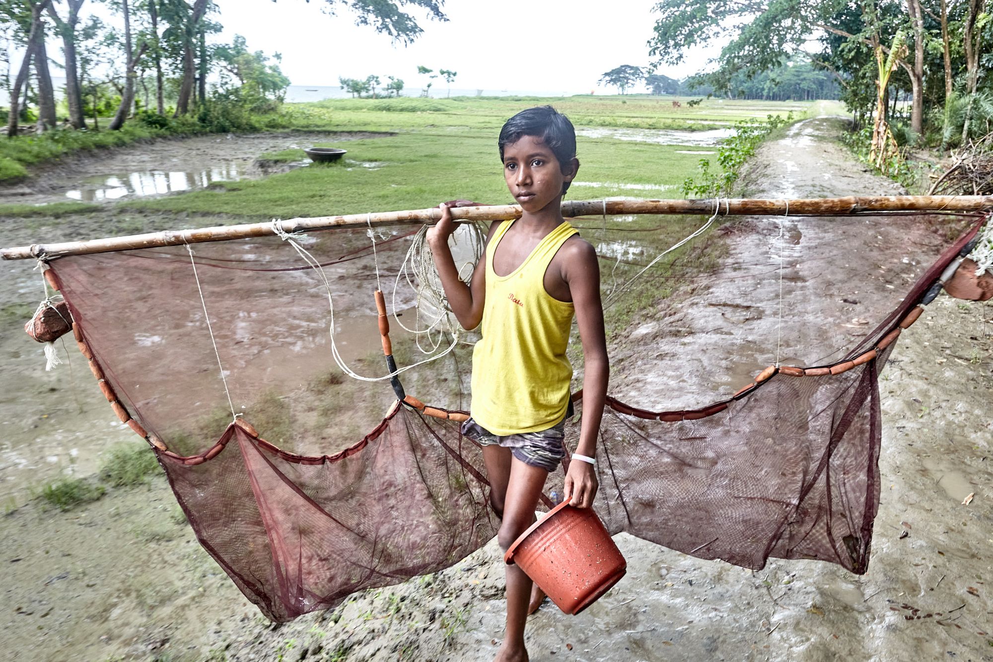 A boy is heading to fish with a net in rural Bangladesh