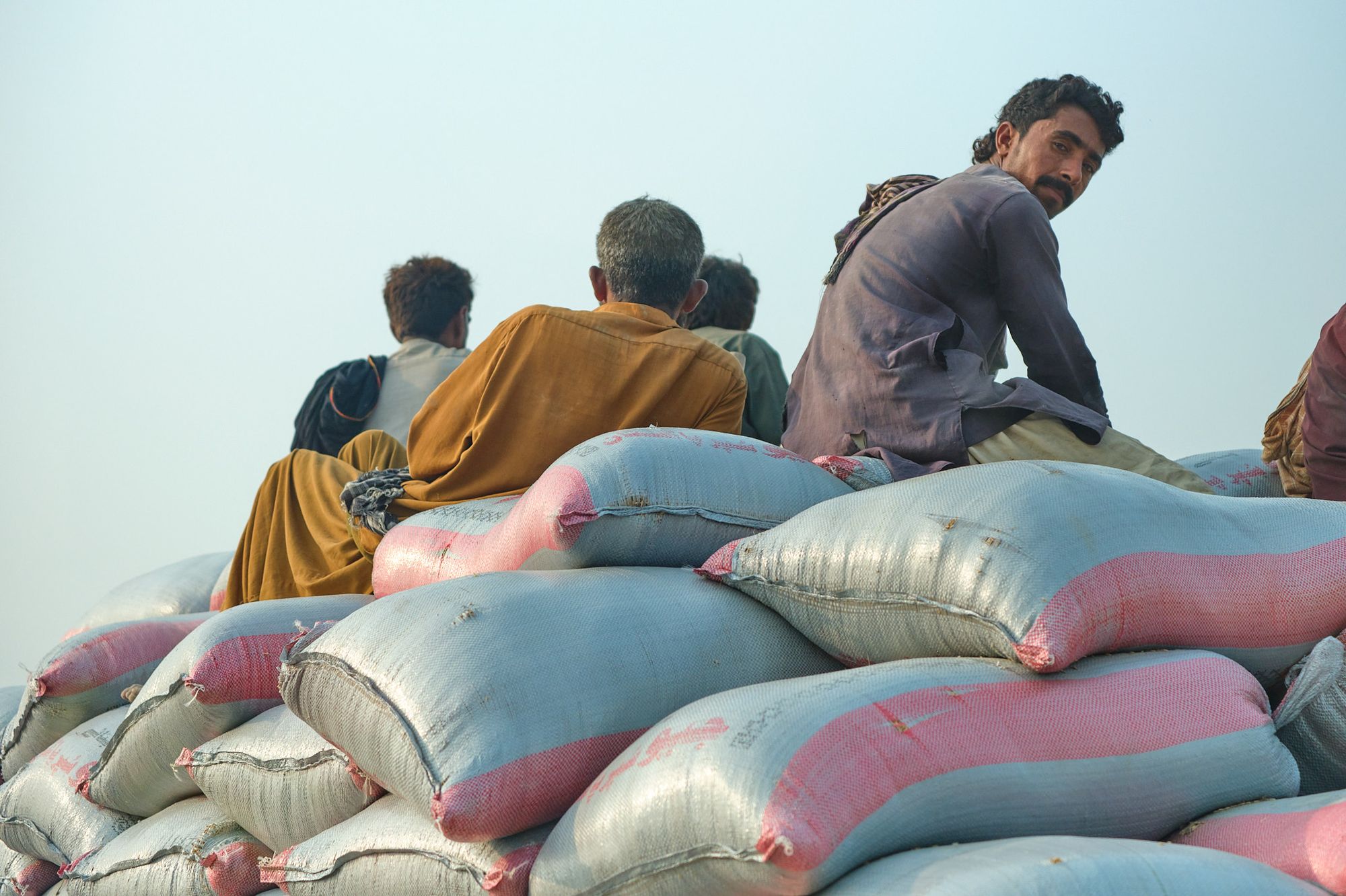 Мen seated on sacks with goods on a truck in southern Pakistan
