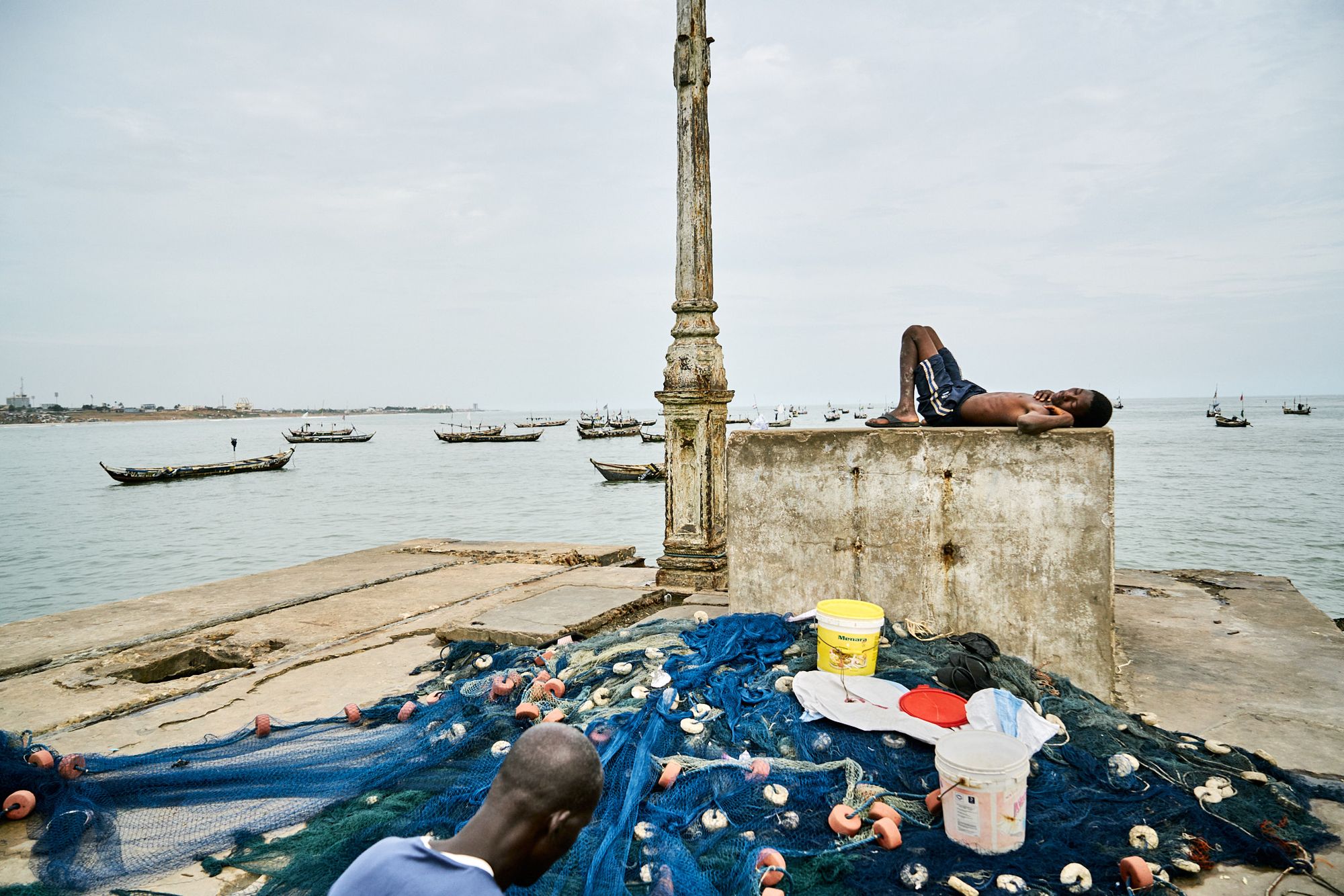 A kid is sleeping on the pier at the old fishing harbour in Jamestown, Accra, Ghana