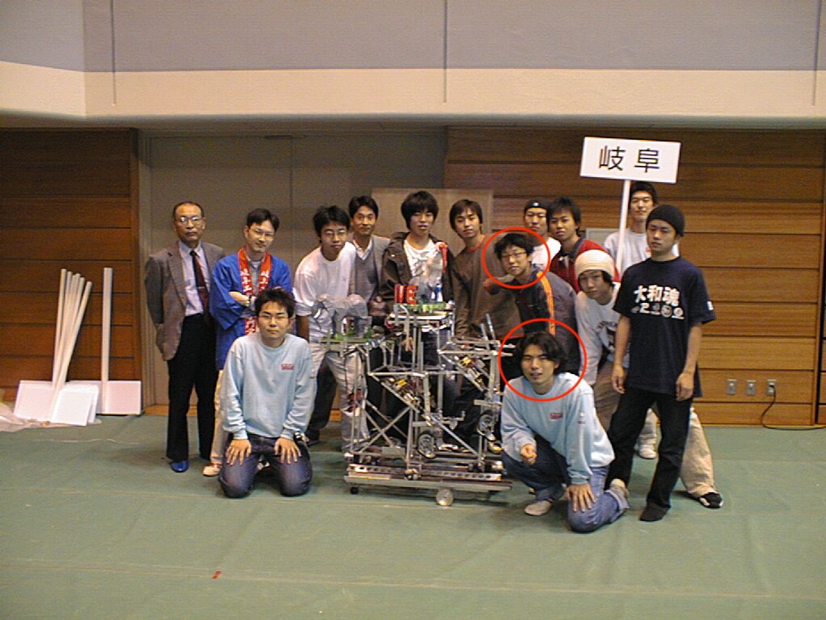 ロボコン2000東海北陸大会での記念写真。上の赤丸が豊吉。下の赤丸が森。中央がポールを登って造形物を載せるロボット。チーム名はCrazy Climberで当時ロボットを作りながら遊んでいたゲームから取った。